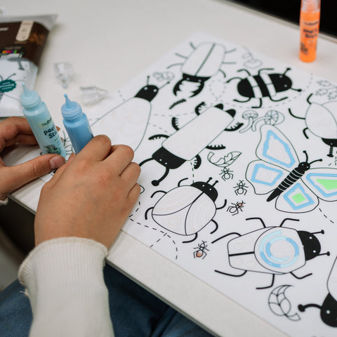 girl coloring on busy bug sensory mat using peel and stick paints
