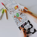 A child colors a HeyDoodle silicone mat from Habitats Above & Below Tales; vivid markers sit on the white table, ready for creative play.