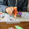 girl coloring on provided plastic sheet using peel and stick paints