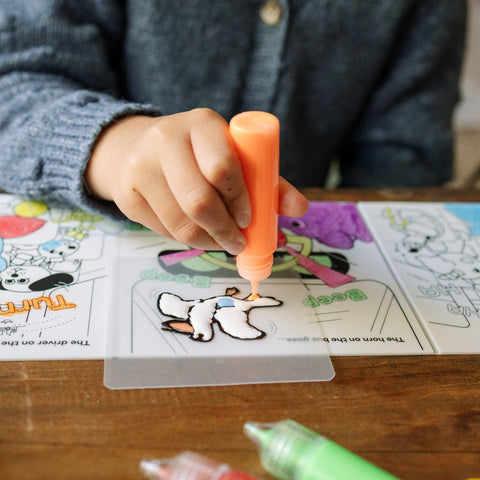 girl coloring on provided plastic sheet using peel and stick paints